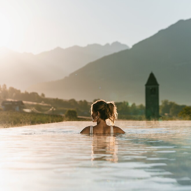 Vista posteriore di donna nella Sky Infinity Pool con sole serale dal bagliore rossastro